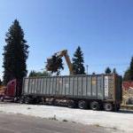 a construction dumpter is being loaded with debris using heavy equipment