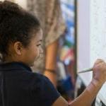 Young student works at a math problem at a white board in a classroom