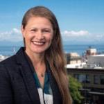 Chandra Hampson smiles for a photo with the city and sound behind her.