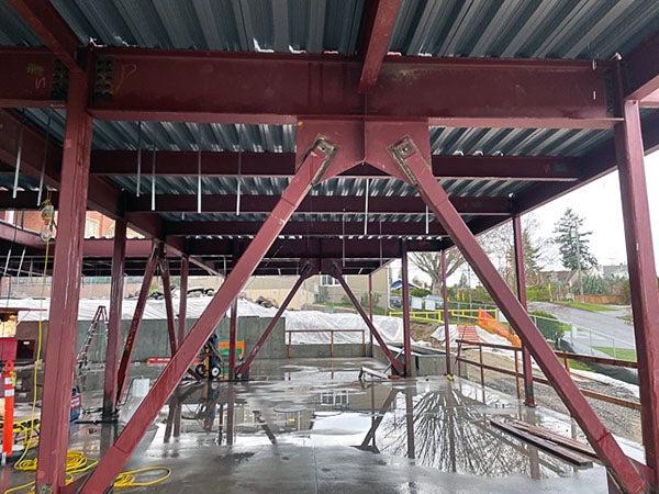 a steel frame has braces and metal decking above a concrete floor