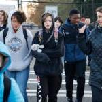 Students and adults walk together across a crosswalk