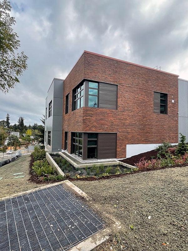 a brick building with a garden has dirt sprayed with greenish gray material