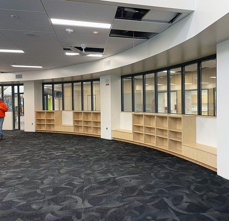 a curved wall with windows has bookshelves below the windows